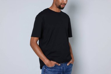 Açık gri arka planda siyah tişört giyen adam, yakın plan. Tasarım için model