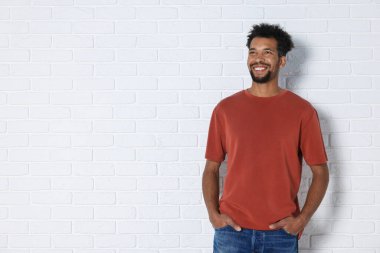 Beyaz duvarın yanında kırmızı tişört giyen bir adam. Tasarım için model