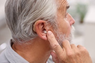 İçeride işitme cihazlı kıdemli adam, yakın plan.