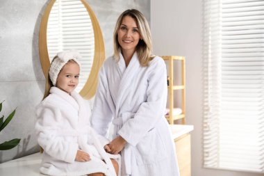 Banyoda bornozlu mutlu anne ve kız. Metin için boşluk