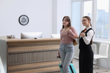 Üniformalı gülen resepsiyonist, misafirleri içeri buyur ediyor, mesaj için yer var.