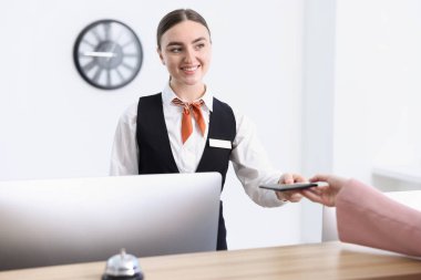 Resepsiyonist, otel odasındaki konuklara pasaport ve otel kartı veriyor.