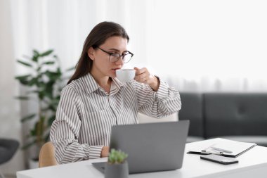 Ofisteki beyaz masada kahve molası veren kadın.