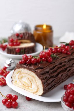 Lezzetli Noel kütüğü (geleneksel Noel pastası) gri desenli masa üzerinde kırmızı frenk üzümü, yakın plan