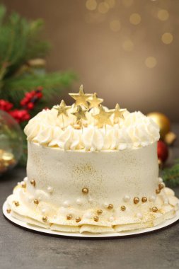 Bulanık ışıklara karşı gri masanın üzerinde Noel dekoru olan lezzetli bir pasta.