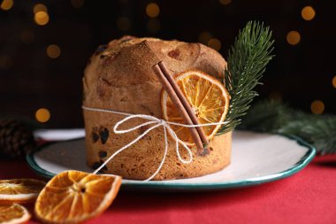 Noel yemeği. Lezzetli Panettone pastası, baharatlar ve arka planda arka planda bulanık ışıklarla süslü bir dekor, yakın plan. Bokeh etkisi