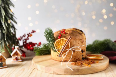 Noel yemeği. Lezzetli Panettone pastası, malzemeler, zencefilli çörekler ve ahşap masa üzerindeki şenlikli dekorlar arka planda bulanık ışıklar, yakın plan. Bokeh etkisi