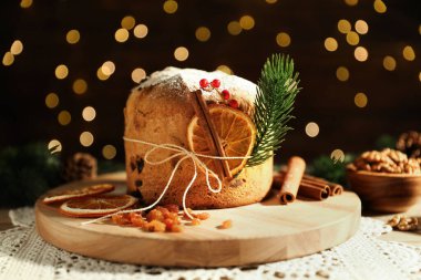 Noel yemeği. Lezzetli Panettone pastası, malzemeler ve arka planda arka planda bulanık ışıklı şenlikli dekor, yakın plan. Bokeh etkisi