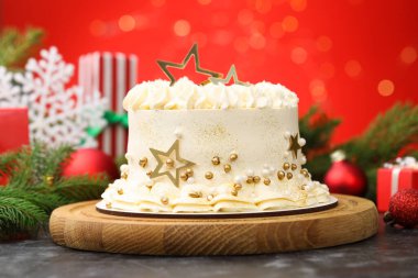 Siyah masanın üzerinde Noel dekoru olan lezzetli pasta kırmızı arka planda bulanık ışıklar, yakın plan