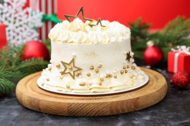 Kırmızı arka planda siyah masanın üzerinde Noel dekoru olan lezzetli pasta, yakın plan.