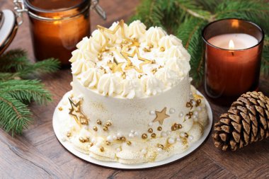 Noel dekorlu lezzetli pasta ve ahşap masada yanan mumlar, yakın plan.