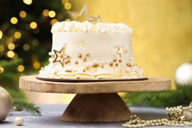 Gri masadaki Noel desenli lezzetli pasta altın arka planda bulanık ışıklar, yakın plan