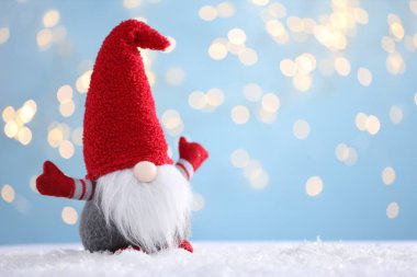 Yapay kardaki komik noel cücesi açık mavi arkaplanlı bulanık ışıklı, yazı için yeri olan. Bokeh etkisi