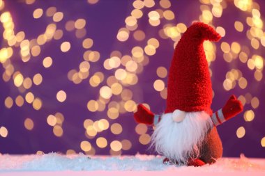 Yapay kardaki komik noel cücesi mor arka plandaki bulanık ışıklara karşı, mesaj için yer var. Bokeh etkisi