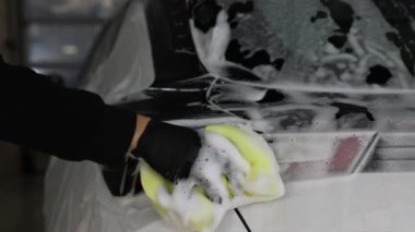 Oto yıkayan adam araba yıkamada süngerle yıkıyor.