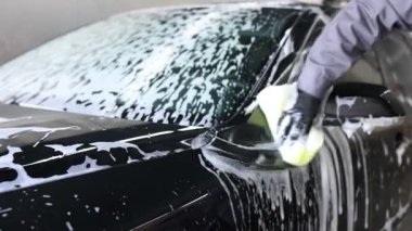 Oto yıkayan adam araba yıkamada süngerle yıkıyor, yakın plan. Kamera hareket ediyor