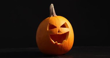 Siyah arka plana balkabağı oyulmuş, yakın plan. Kamera ileri gidiyor