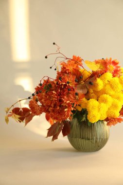 Sonbahar atmosferi. Güzel çiçekli vazo ve bej arka planda böğürtlen, yakın plan.