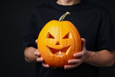 Cadılar Bayramı kutlaması. Siyah arka planda balkabağı olan adam, yakın plan.