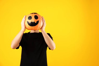 Cadılar Bayramı kutlaması. Turuncu arka planda çizilmiş ürkütücü suratlı balkabağı tutan adam, mesaj için boşluk