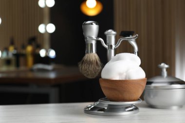 Berber dükkanında traş fırçası, tıraş bıçağı ve bir kase köpükle ahşap masa. Metin için boşluk