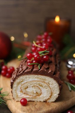 Lezzetli Noel kütüğü (geleneksel Noel pastası) ahşap masa üzerinde kırmızı frenk üzümü, yakın plan