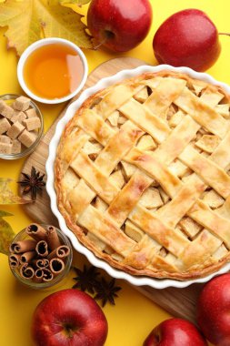 Lezzetli ev yapımı elmalı turta ve sarı arka planda malzemeler.