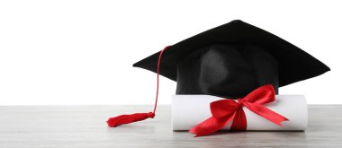 Mezuniyet şapkası ve diploması beyaz arka plana karşı ahşap masada.