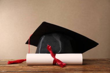 Mezuniyet şapkası ve diploması ahşap masada, yakın plan.