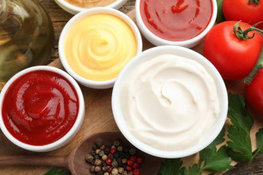 Tabaklardaki farklı soslar ve ahşap masa üzerindeki malzemeler düz.