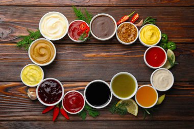 Tabaklardaki farklı soslardan yapılmış çerçeve ve ahşap masa üzerindeki malzemeler düz. Metin için boşluk