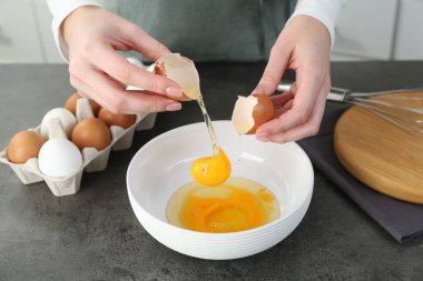 Mutfaktaki gri masada yumurta kıran kadın, yakın plan.