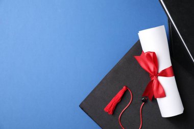 Diploma, mezuniyet şapkası ve mavi arka planda kırtasiye malzemesi. Metin için boşluk