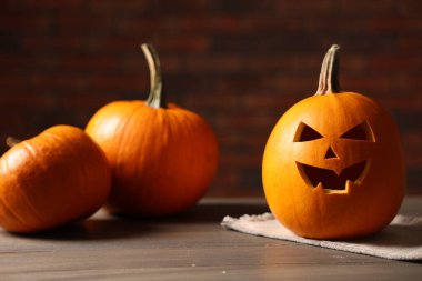 Cadılar Bayramı kutlaması. Tuğla duvara karşı ahşap masada oyulmuş balkabakları, yakın plan.