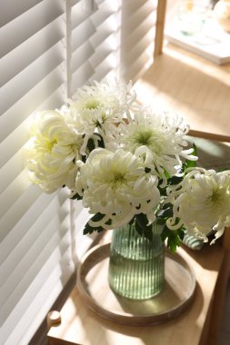 Güzel beyaz kasımpatı çiçekleri vazoda, ahşap masada.