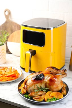 Lezzetli ızgara tavuk biberiyeli, sebzeli ve beyaz mermer masada kızartma makinesi.