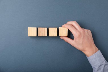 Gri arka planda tahta küpleri olan adam, üst manzara.