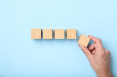 Açık mavi arka planda tahta küpleri olan adam, üst manzara.