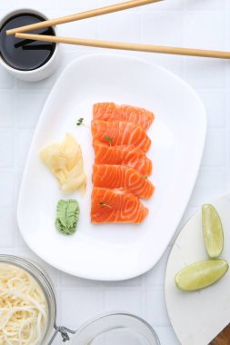 Mikro yeşillikli taze somon balığı, wasabi, zencefil ve soya sosu açık fayanslı masada servis edilir.