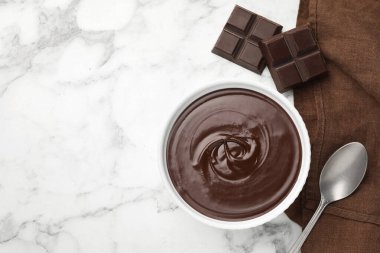 Erimiş çikolata kasede, parçalar ve kaşık beyaz mermer masada, düz yerde. Metin için boşluk