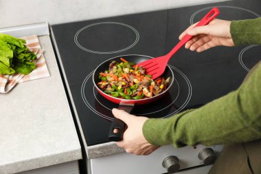 Kızartma tavasında taze sebze ve spatula karıştıran kadın, yakın plan.