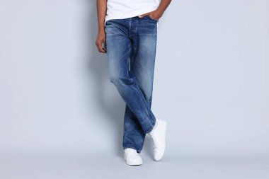 Açık gri arka planda şık kotlar giyen adam, yakın plan.