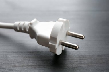 Siyah ahşap masada fişi olan elektrik kablosu, yakın plan.