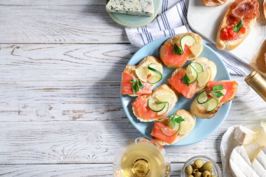 Somon, salatalık, limon, prosciutto ve beyaz ahşap masada şarap ile nefis bruschetalar. Metin için boşluk