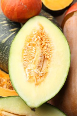 Arka plan olarak bir sürü taze balkabağı ve kavunun yarısı görünüyor. Su kabağı ailesi