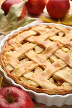 Lezzetli ev yapımı elmalı turta, elmalar ve kuru yapraklar masada, yakın plan.