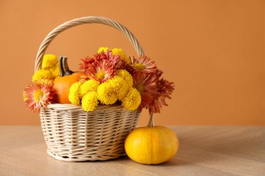 Güzel bir sonbahar kompozisyonu. Çiçekler ve balkabakları ahşap masa üzerinde turuncu arka planda. Metin için boşluk
