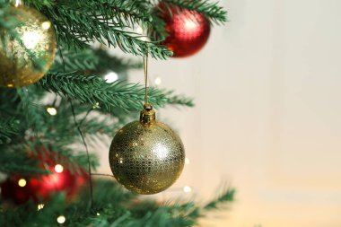 Noel süsleri ve şenlik ışıkları köknar ağacının dallarında bulanık gri arka planda asılı, yakın plan. Metin için boşluk