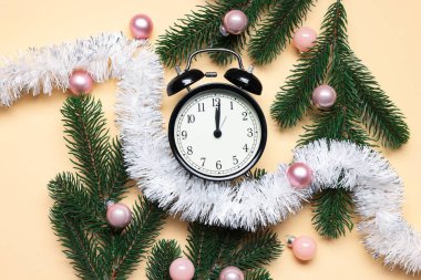 Alarm saati, köknar ağacı dalları, bej arka planda takılar ve süsler, düz bir zemin. Yeni yıl tebrik kartı.