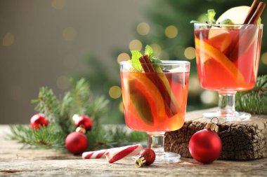 Gözlüklü, baharatlı ve Noel dekorlu kokteyl. Arka planda, bulanık ışıklar ve yazı için yer olan ahşap masa. Bokeh etkisi